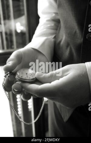 Dettaglio delle mani di un uomo elegante che guarda il suo orologio da tasca Foto Stock