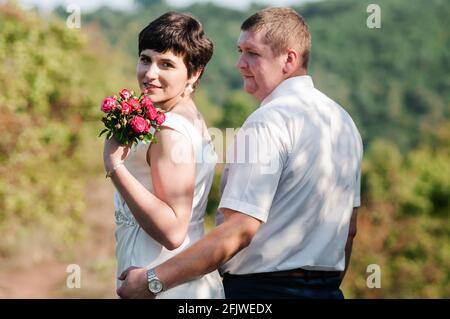 Abbraccio e bacio degli sposi novelli sullo sfondo della foresta Foto Stock