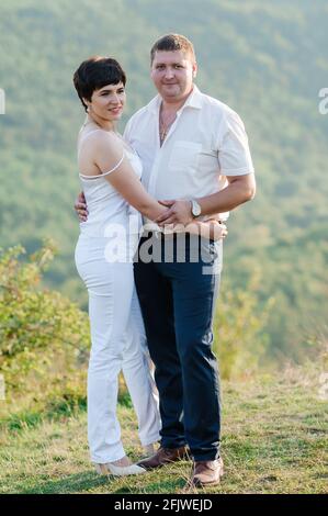 Abbraccio e bacio degli sposi novelli sullo sfondo della foresta Foto Stock