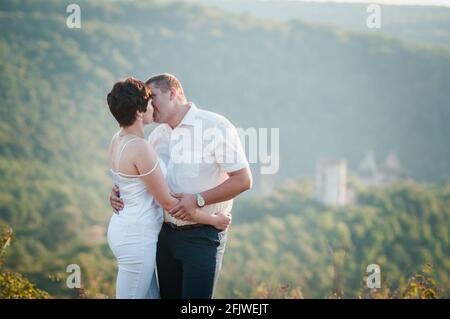 Abbraccio e bacio degli sposi novelli sullo sfondo della foresta Foto Stock