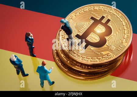 Riunione di affari circa la decisione di investimento per il concetto di bitcoin: Statuette dell'uomo d'affari in miniatura in piedi vicino al mucchio di bitcoin dorato lucido sopra Foto Stock