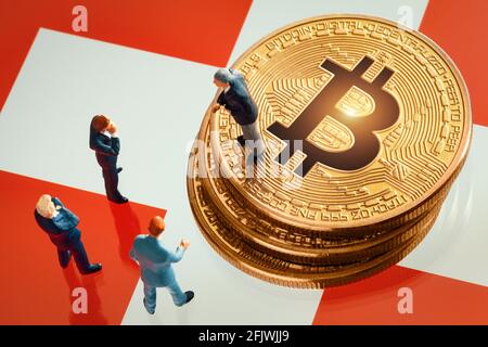 Riunione di affari circa la decisione di investimento per il concetto di bitcoin: Statuette dell'uomo d'affari in miniatura in piedi vicino al mucchio di bitcoin dorato lucido sopra Foto Stock