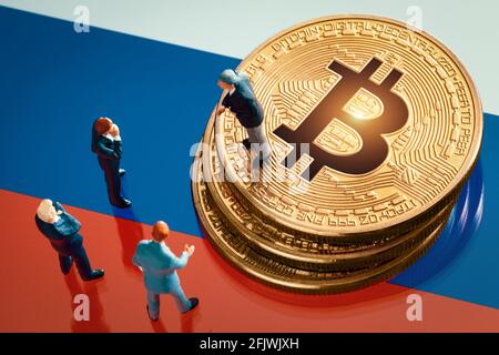 Riunione di affari circa la decisione di investimento per il concetto di bitcoin: Statuette dell'uomo d'affari in miniatura in piedi vicino al mucchio di bitcoin dorato lucido sopra Foto Stock