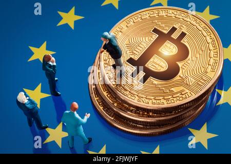 Riunione di affari circa la decisione di investimento per il concetto di bitcoin: Statuette dell'uomo d'affari in miniatura in piedi vicino al mucchio di bitcoin dorato lucido sopra Foto Stock