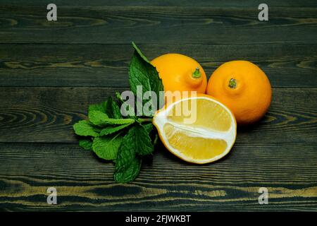 limoni su sfondo di legno scuro con foglie di menta Foto Stock