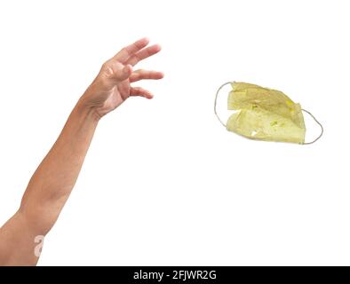 Un braccio che getta via una maschera gialla sporca. Foto Stock