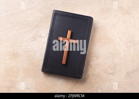 Croce di legno sulla Bibbia su sfondo di marmo. Ricordo del sacrificio di Gesù e della risurrezione di Cristo. Pasqua. Concetto di Eucaristia. Cristianesimo Foto Stock