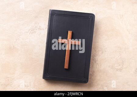 Croce di legno sulla Bibbia su sfondo di marmo. Ricordo del sacrificio di Gesù e della risurrezione di Cristo. Pasqua. Concetto di Eucaristia. Cristianesimo Foto Stock