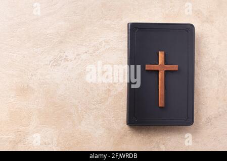 Croce di legno sulla Bibbia su sfondo di marmo. Ricordo del sacrificio di Gesù e della risurrezione di Cristo. Pasqua. Concetto di Eucaristia. Cristianesimo Foto Stock