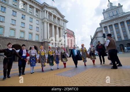 Sofia, Bulgaria - Apr 20 2021: L'uomo e le donne in abiti tradizionali ballano davanti all'Assemblea nazionale e al Consiglio dei ministri Foto Stock