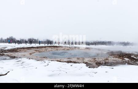 I turisti aspettano l'eruzione del geyser nell'Islanda sudoccidentale. Il paesaggio di Geysir nella stagione invernale Foto Stock