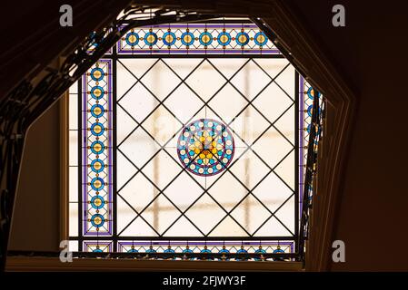 Una colorata finestra di vetro colorato posta sul soffitto, composta da piastrelle di vetro rotonde e quadrate che illuminano l'interno delle scale. Foto Stock