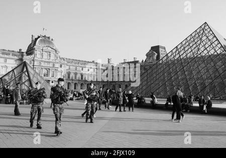 PARIGI, FRANCIA - 12 MARZO 2016: I soldati pattugliano vicino al museo del Louvre. La Francia ha rafforzato le misure di lotta contro la criminalità e il terrorismo. Bianco nero Foto Stock