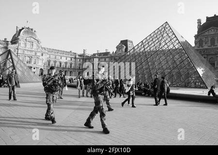 PARIGI, FRANCIA - 12 MARZO 2016: I soldati pattugliano vicino al museo del Louvre. La Francia ha rafforzato le misure di lotta contro la criminalità e il terrorismo. Bianco nero Foto Stock