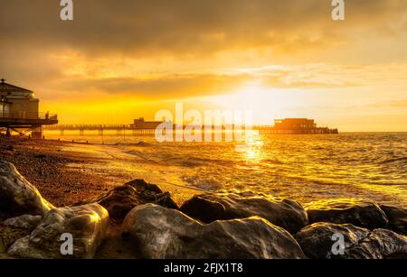 Il sorgere del sole oltre il molo e il mare in autunno a Worthing West Sussex, in Inghilterra, Regno Unito. Foto Stock