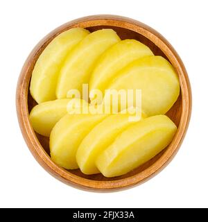 Patate cotte e tagliate a fette, in una ciotola di legno. Patate cerose bollite e pelate, tagliate a fette spesse. Un contorno o per un'insalata. Primo piano, dall'alto Foto Stock