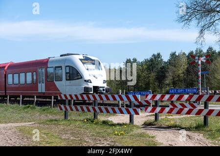 Passaggio a livello incustodito per ciclisti e pedoni, con treno passante Foto Stock