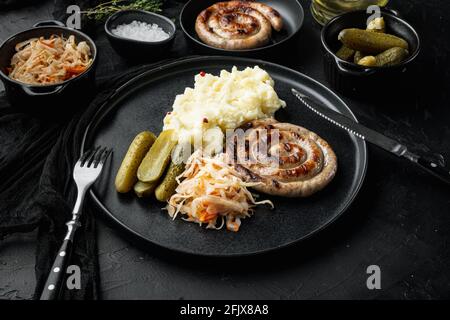 Salsicce tradizionali tedesche con purè di patate e Sauerkraut, su sfondo nero Foto Stock