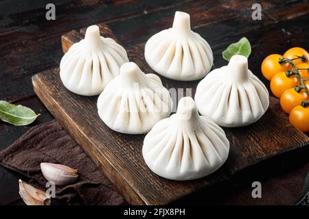 Gnocchi cinesi Baozi non cotti. Set di gnocchi aziani, su vecchio tavolo di legno scuro sfondo Foto Stock