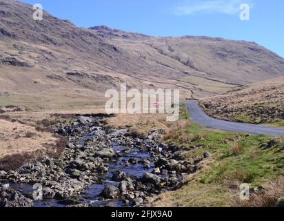 Strada accanto al fiume Duddon e Wrynose Bottom, guardando da Cockley Beck, Duddon Valley, Cumbria, Regno Unito. Foto Stock