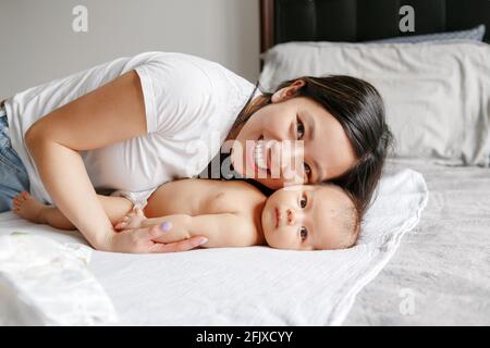 Festa della mamma. Felice madre asiatica hugging figlio neonato cinese. Foto Stock