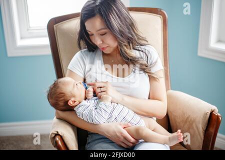 Festa della mamma. Felice madre asiatica che tiene il bambino neonato figlio. Foto Stock