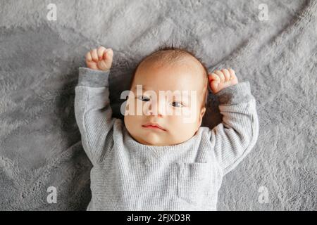 Carino due mesi neonato asiatico cinese bambino ragazzo sdraiato sul letto guardando. Foto Stock