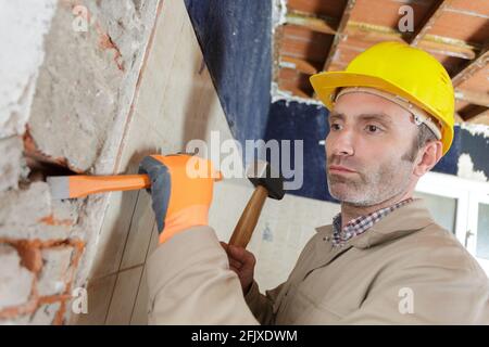 costruttore maschio che rompe un muro Foto Stock