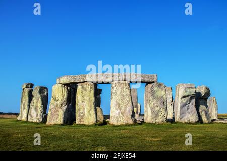 Primo piano di pietre stonehenge con tre architravi su quattro enormi montanti in primo piano sotto un cielo molto blu in una giornata estiva con un till Foto Stock
