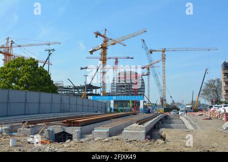 Grandi gru che costruiscono edifici alla nuova stazione ferroviaria di Jiaxing nord, mentre le piste per una nuova linea di transito sono costruite per portarla. Foto Stock