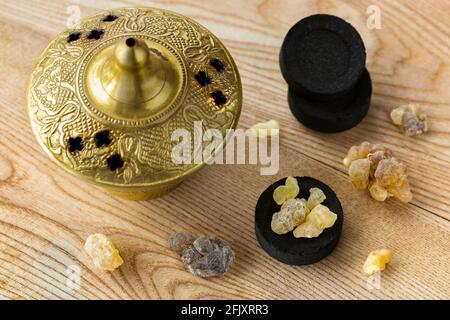 Gomma di resina gialla aromatica dell'albero sudanese di Frankincense sui carbonai arabi per bruciare l'incenso aromatico nel bruciatore di ottone. Foto Stock