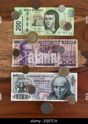 Pesos messicani, banconote, banconote e monete su sfondo di legno. Valuta messicana Foto Stock