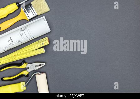 diversi strumenti di lavoro e progetti architettonici su sfondo grigio scuro. vista dall'alto Foto Stock