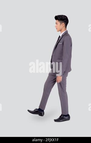 Giovane uomo d'affari asiatico in movimento a piedi vestito isolato su sfondo bianco, ritratto di dirigente o manager, felice uomo d'affari bello e intelligente Foto Stock