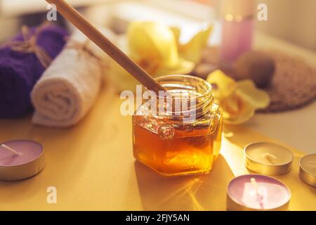 Il miele viene versato nel vaso. Concetto di cura della spa. Cura naturale della pelle domestica. Sfondo sfocato. Bella luce. Foto Stock