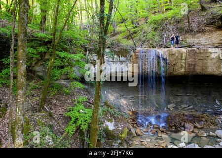 Giovane coppia in piedi in una bella cascata, ruscello che scorre attraverso la fitta foresta verde, Pasjak Slovenia Foto Stock