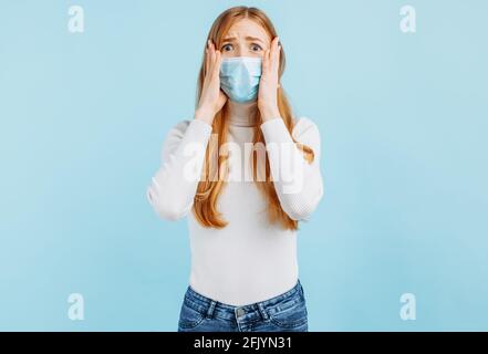 Giovane donna eccitata che guarda gli occhi larghi alla bocca di copertura della macchina fotografica con le mani sullo sfondo blu isolato dello studio con spazio per la copia Foto Stock