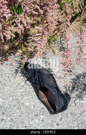 Scarpa nera femminile abbandonata sul marciapiede in Italia Foto Stock