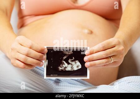 Immagine del bambino nelle mani della donna vicino al pancia grande incinta Foto Stock