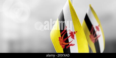 Piccole bandiere nazionali del Brunei su una luce sfocata sfondo Foto Stock
