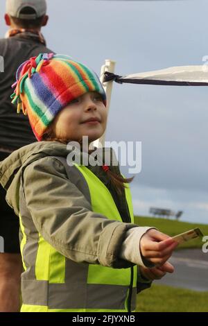 Troon 5k Park Run lungo il lungomare di Troon, Ayrshire, Scozia, Regno Unito il più giovane aiutante era la coppiglia di Eilidh di 6 anni vista qui consegnando le scorciatoie di tempistica Foto Stock