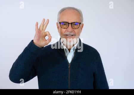 felice positivo bel vecchio uomo mostra ok segno su sfondo bianco. Foto Stock