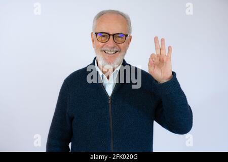 felice positivo bel vecchio uomo mostra ok segno su sfondo bianco. Foto Stock