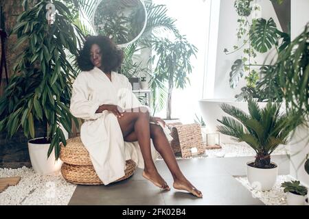 Donna prety afroamericana in un accappatoio bianco in un bagno Foto Stock