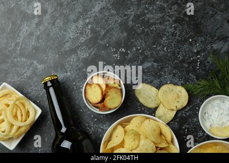 Spuntini diversi e una bottiglia di birra su sfondo nero fumé Foto Stock