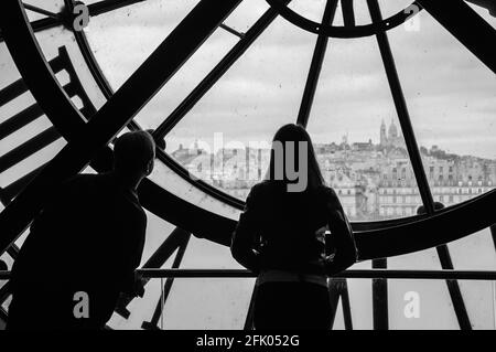 PARIGI, FRANCIA - 6 APRILE 2014: Sagome di un uomo non identificato e di una donna che guarda attraverso l'orologio con numeri romani nel museo D'Orsay sulla t Foto Stock