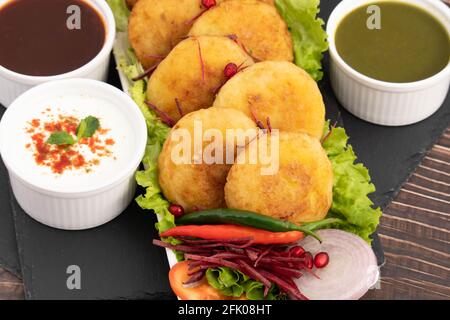 Alo Tikki, conosciuto anche come Alu Ki Tikkia, è condito Frittatine o frittatine di patate bollite usate in vari indiani Cibo di strada Masala Chaat spuntini Foto Stock