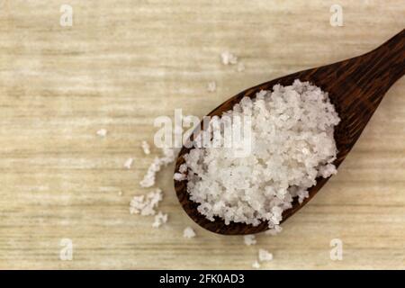 Fiore di sale, raccolto da strato sottile su superficie di acqua di mare, in cucchiaio di legno. Chiamato Fleur de sel in francese, vista dall'alto con copyspace Foto Stock