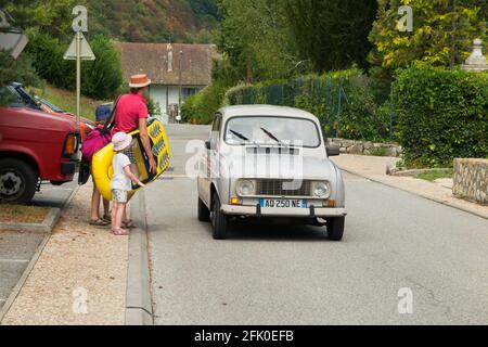 Renault 4 L conducente guida su una strada vicino alle Alpi francesi in Francia. Il conducente sta parlando con i pedoni / chiedendo indicazioni. (101) Foto Stock