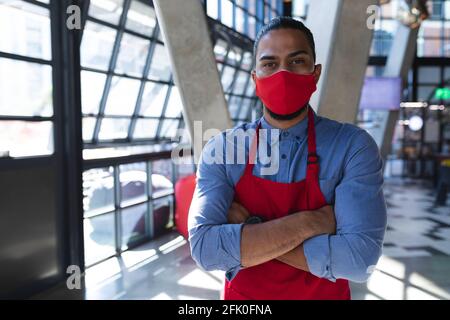 Ritratto del barista maschile di razza mista che indossa la maschera facciale caffè Foto Stock